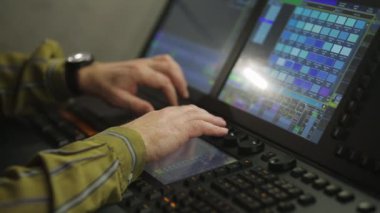 Konsoldaki bir erkek ışıklandırma yönetmeni şov için sahne ışığını programlıyor.