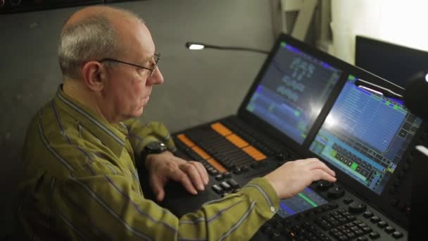 A male engineer illuminator at the remote control programs the stage light for the show. — Stock Video