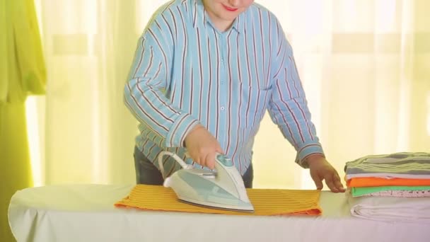 Mujer ama de casa planchar ropa de colores en una tabla de planchar — Vídeo de stock