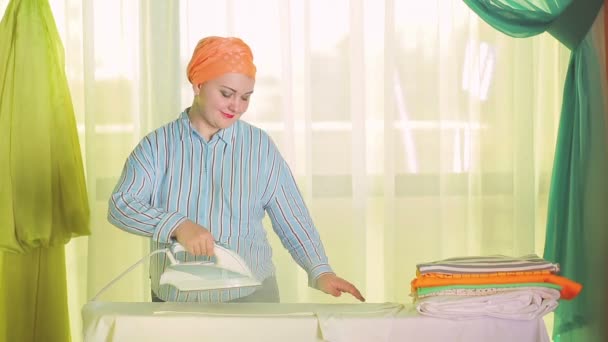 Wanita ibu rumah tangga menyetrika pakaian berwarna di papan setrika — Stok Video