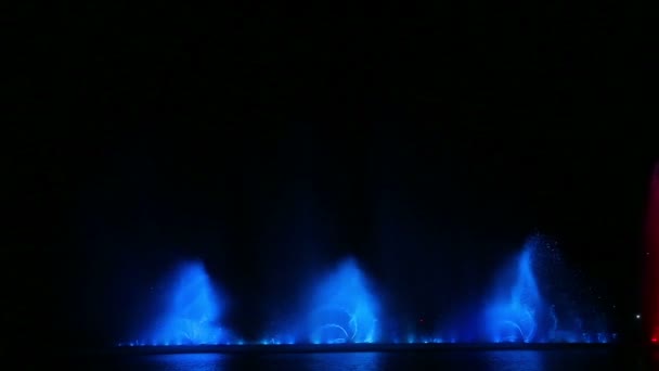 Ночное зрелище фонтанов с разноцветным блеском отражается в воде — стоковое видео
