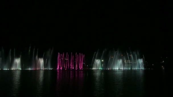 Un espectáculo nocturno de fuentes multicolores brillantes reflejados en el agua — Vídeo de stock