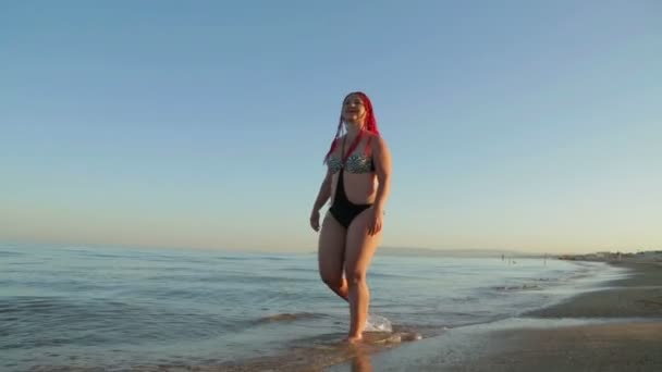 Una donna in costume da bagno cammina lungo la spiaggia — Video Stock