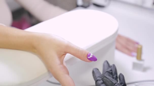 Női manikűrös egy szépségszalonban díszíti a körmök egy ügyfél strasszos — Stock videók