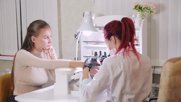 Női manikűrös kesztyűvel egy szépségszalonban csinál egy hardver manikűr egy ügyfél alkalmazása előtt egy gél bevonat — Stock videók