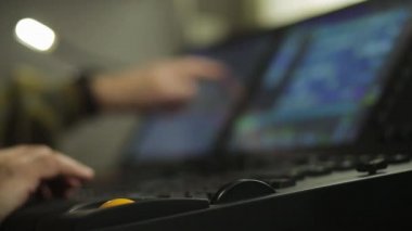 Uzaktan kumandadaki aydınlatma yönetmeni erkek program için sahne ışığını programlıyor. Bulanık kare.