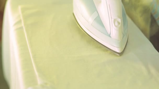 Утюг разглаживает белое белье на гладильной доске — стоковое видео