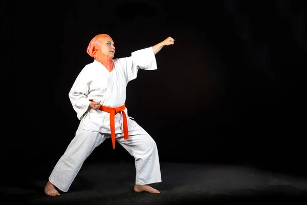 Junge Muslimin in Kimono und Schal beim Karatetraining vor schwarzem Hintergrund. — Stockfoto