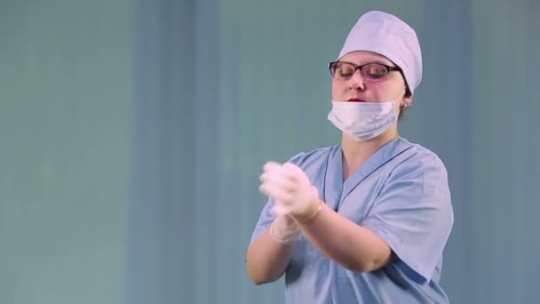 Una doctora se pone guantes médicos y una máscara se prepara para un examen de personas con sospecha de coronavirus . — Vídeos de Stock