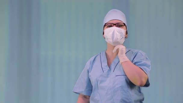 Médico feminino em uma máscara médica tosse enquanto se esconde com uma mão enluvada — Vídeo de Stock