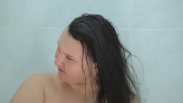 Uma mulher morena pinta seu cabelo com uma escova e pente — Vídeo de Stock