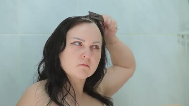 Eine brünette Frau färbt sich die Haare mit Pinsel und Kamm — Stockvideo