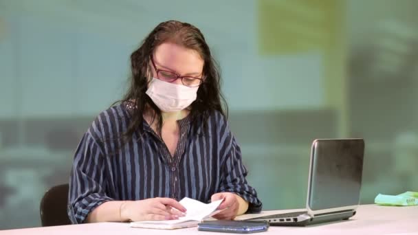 Жінка в офісі виконує роботу в медичній масці — стокове відео