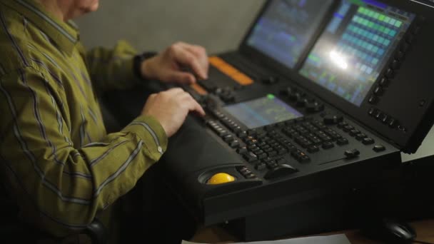 Een mannelijke illuminator op de afstandsbediening programmeert het podiumlicht voor de show — Stockvideo