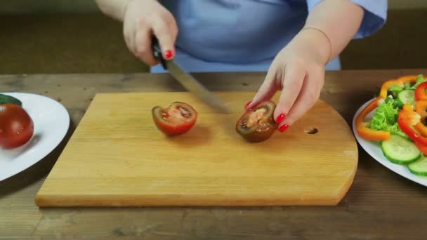 女性はサラダのために木の板に黒いトマトをスライスします。タイムラプス. — ストック動画