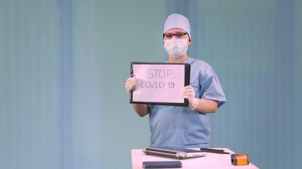 Женщина-врач в медицинской маске призывает не поддаваться панике, связанной с коронавирусом, и снимает маску — стоковое видео