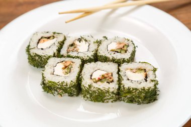 Somonlu rulo ve çubuklu beyaz bir tabakta dereotu..