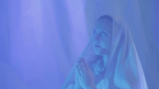 A young Muslim woman in white makes a prayer before the wedding behind a white curtain — Stock Video