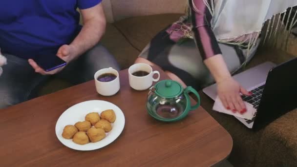 A married couple in protective masks in quarantine for the prevention of coronavirus at home on the couch disinfects their hands on a smartphone and a computer — Stock Video