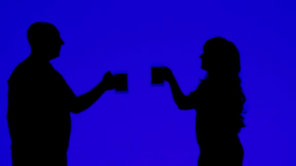 Silhouette di una donna e un uomo che bevono birra da tazze su sfondo blu — Video Stock