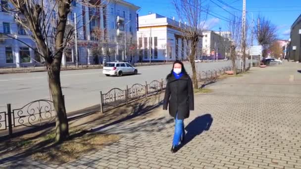 2020年4月4日ロシア、レニン・アベニュー、イワノヴォ市。コロナウイルスと戦うために隔離中に捨てられた街を歩く医療マスクの女性 — ストック動画