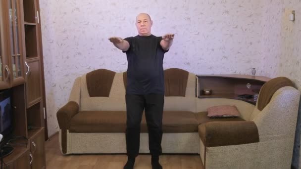 Un hombre en una sala de estar durante un entrenamiento hace ejercicios de swing de piernas — Vídeos de Stock