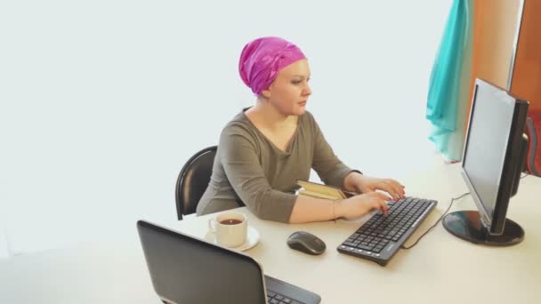 En judisk kvinna i en huvudbonad på ett kontor arbetar på en dator — Stockvideo