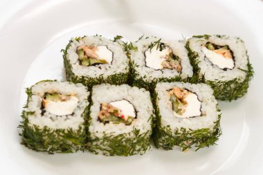 Somonlu rulo ve çubuklu beyaz bir tabakta dereotu..