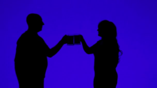 Silhouette d'une femme et d'un homme buvant de la bière dans des tasses sur fond bleu — Video