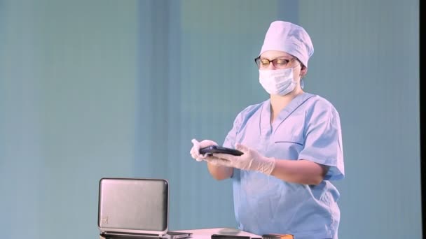 Un medico donna in una maschera medica mostra come disinfettare un posto di lavoro . — Video Stock