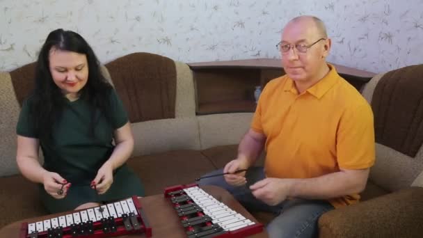 Un hombre y una mujer en casa jugando con teléfonos de metal . — Vídeo de stock