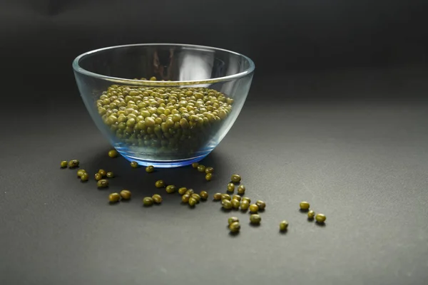 黒の背景に緑のシリアルムン豆とガラス瓶. — ストック写真