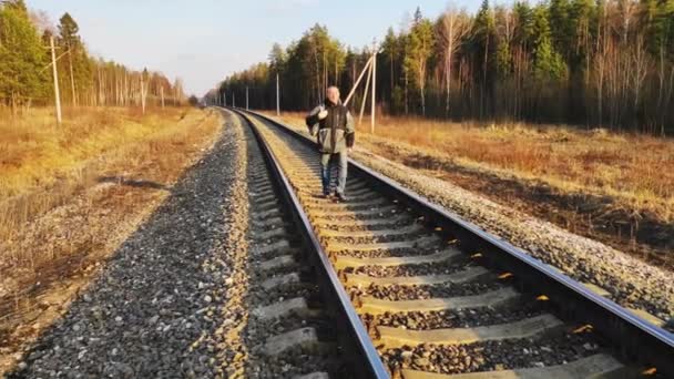 Уставший возвращается домой на железнодорожных путях с чемоданом. . — стоковое видео