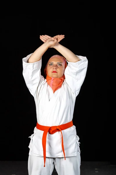 Young muslim woman in kimono and shawl during karate training over black background. Shooting in full growth. — Stock Photo, Image