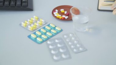 Tıbbi eldivendeki bir el tabaktan ilaç ve su alır.