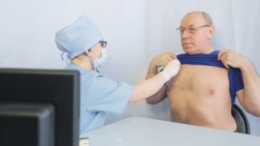 Kadın bir doktor, zatürree şüphesiyle steteskobu olan bir adamı dinler.