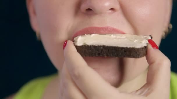 Une jeune femme à l'appétit mâche un sandwich au fromage à la crème — Video