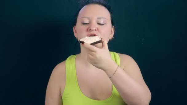 Een jonge vrouw na een hongerig dieet met een eetlust kauwt op een room kaas sandwich — Stockvideo