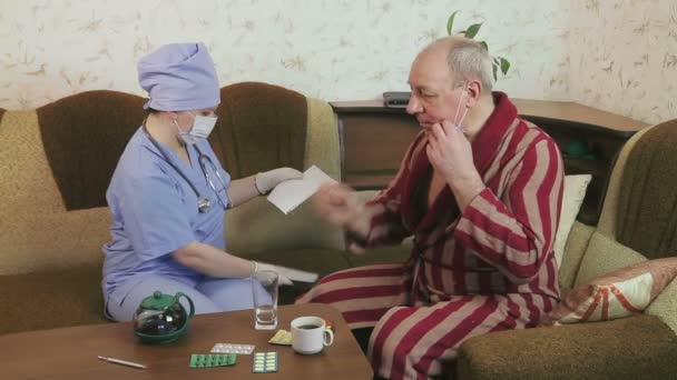 Ženský lékař poučuje nemocničního pacienta doma, aby užíval léky. Muž pije prášky. — Stock video