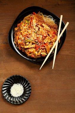 Mantarlı siyah tabak ve ahşap bir masa ve çubuk üzerinde tavuk..