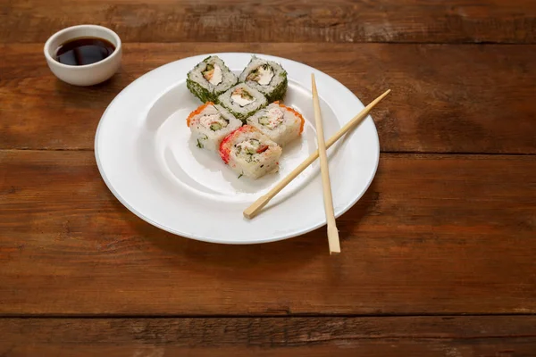 Assorted different fish rolls on a white plate soy sauce. — Stock Photo, Image