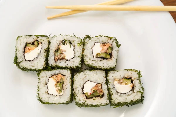 Rolls with salmon and dill on a white plate with chopsticks. — Stock Photo, Image