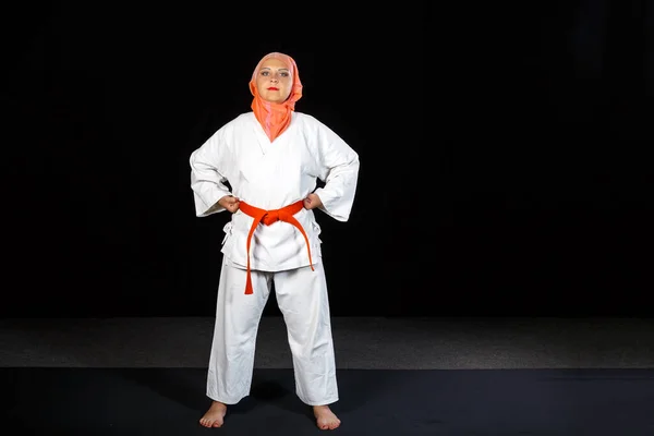 Young muslim woman in kimono and hijab in karate training over black background — Stock Photo, Image