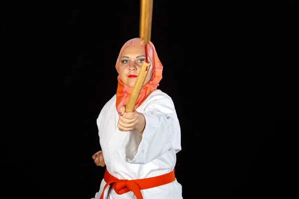 Мусульманка в кимоно и хиджабе на занятиях карате тренируется с нунчаками — стоковое фото