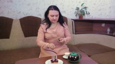 Genç bir kadın doğum gününü karantinada tek başına kutlar. Coronavirus pastadaki mumları yakar..