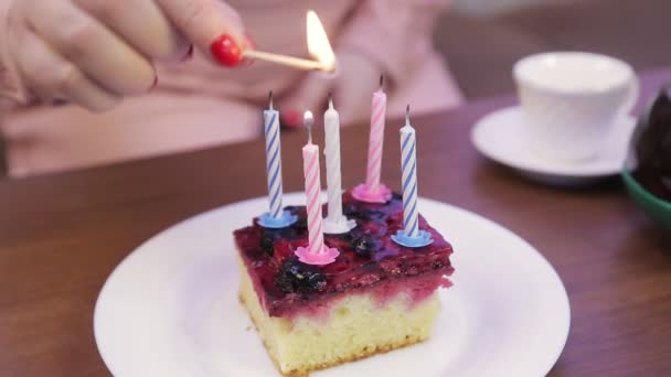 Женщина зажигает свечи на маленьком праздничном торте — стоковое видео