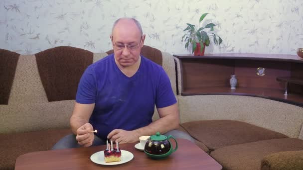 Ένας λυπημένος άνθρωπος γιορτάζει τα γενέθλιά του μόνος στην καραντίνα, ο κορωναϊός ανάβει κεριά στην τούρτα.. — Αρχείο Βίντεο