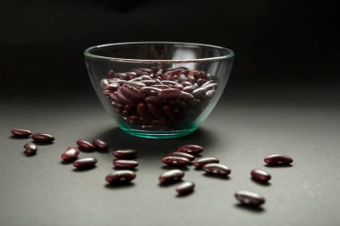 Siyah arkaplanda kırmızı fasulye olan cam kavanoz..