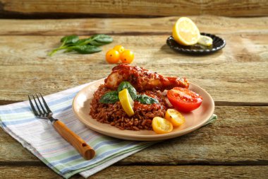 Tavuk budu, domates soslu kırmızı pilav, ahşap bir masa ve keten peçete..
