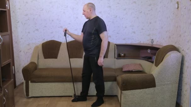 Человек в гостиной на тренировке делает упражнения на растяжку с расширителем — стоковое видео